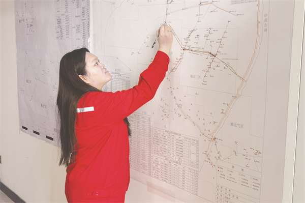 1735131506966377.jpg 4-12 3 图为伍刘惠正在室内利用油井悬挂图查找井位。.jpg