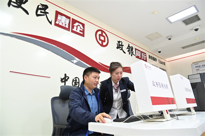5 （图片新闻）2024年10月30日，在位于重庆市沙坪坝区的中国银行重庆沙坪坝支行的政务服务便民区，银行工作人员协助市民办理相关业务。 (1).JPG